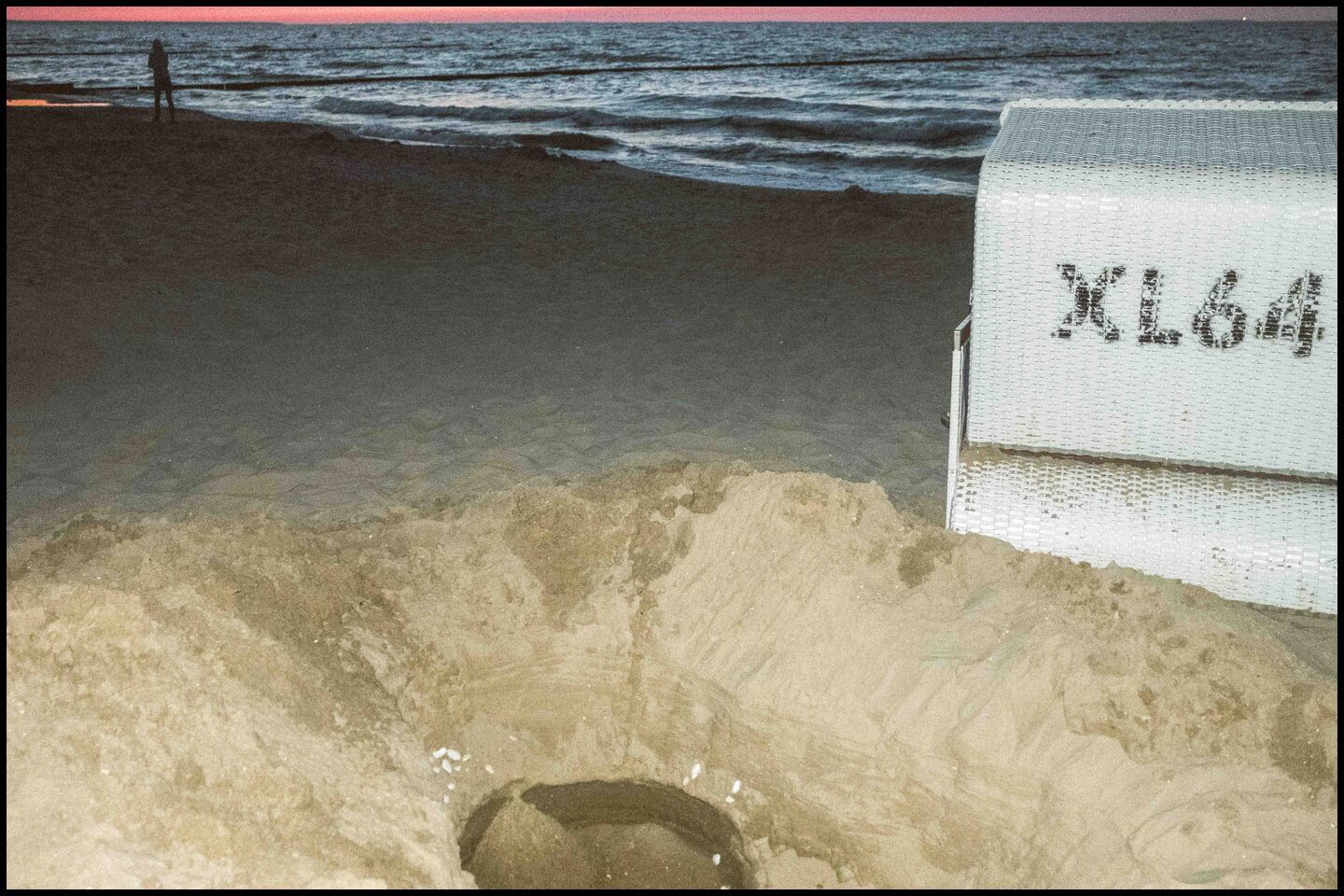 a dug hole, beach chair and a person on the beach